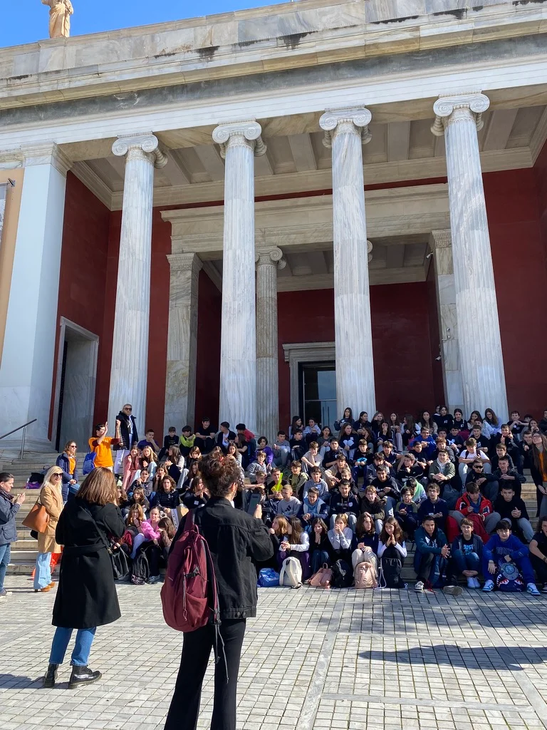 Large group of students gathered outside a historic museum building during an educational school visit.